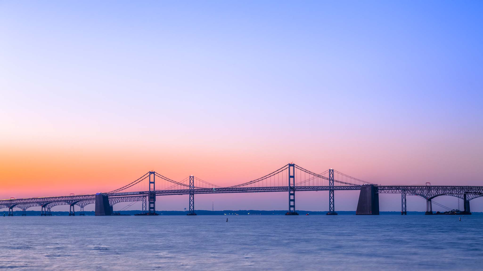 Chesapeake Bay Bridge with Beautiful Sunrise A beautiful sunrise over the calm waters under the Chesapeake Bay Bridge. The steel and concrete cantilever and suspension bridge near Baltimore, MD, stretches across the Chesapeake Bay.